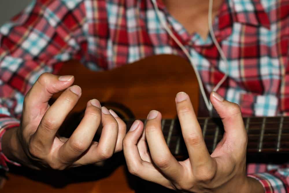 man in plaid shirt having problem with his fingers