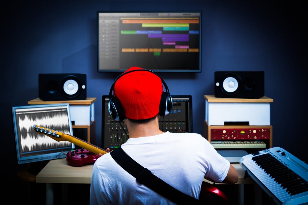 Back of male musician playing guitar in recording studio