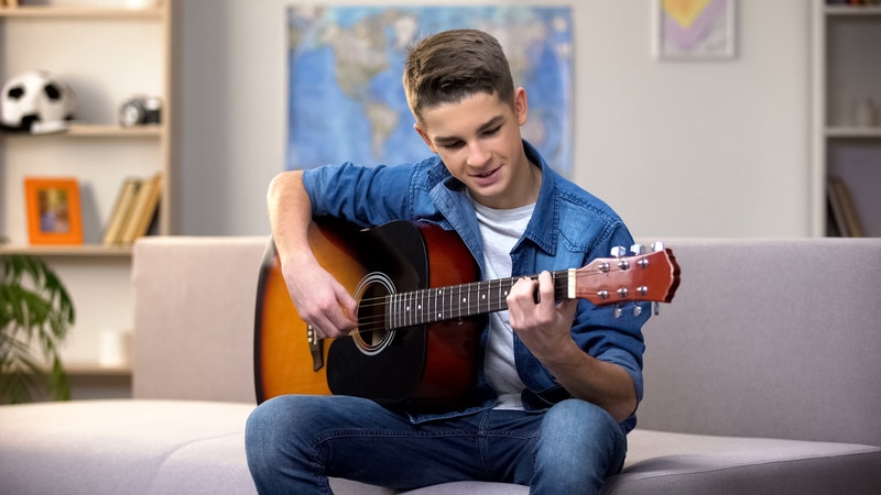 Cheerful Caucasian teenager playing guitar