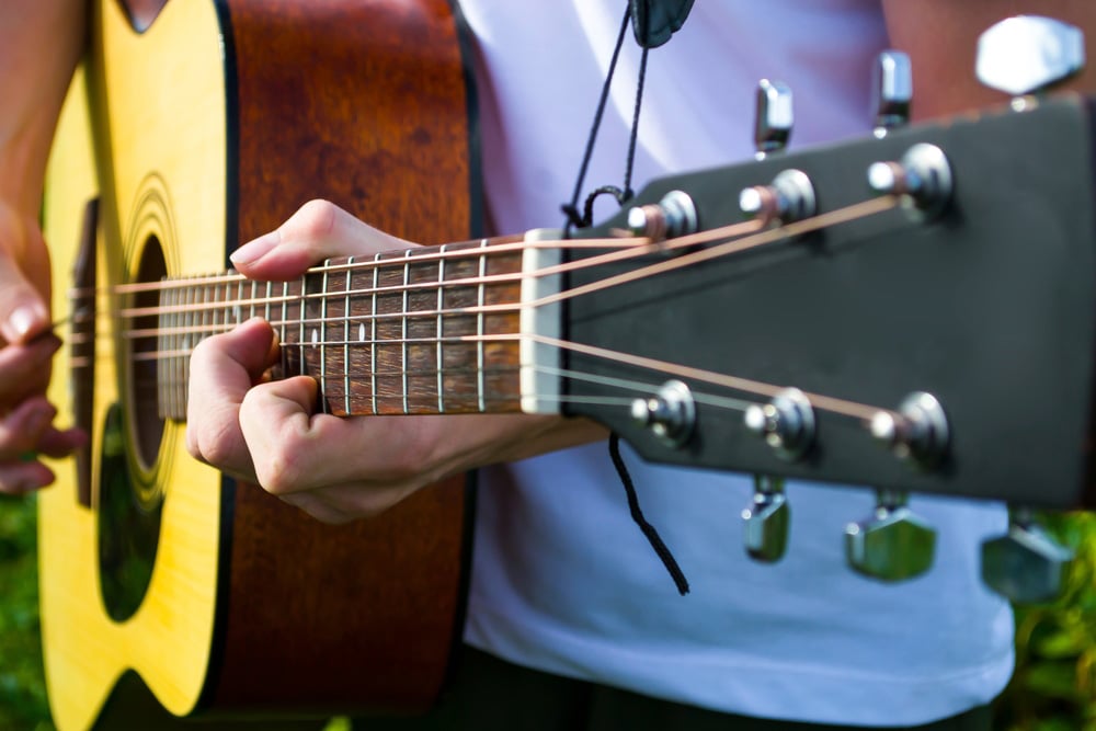 Happy young man playing guitar outside the home